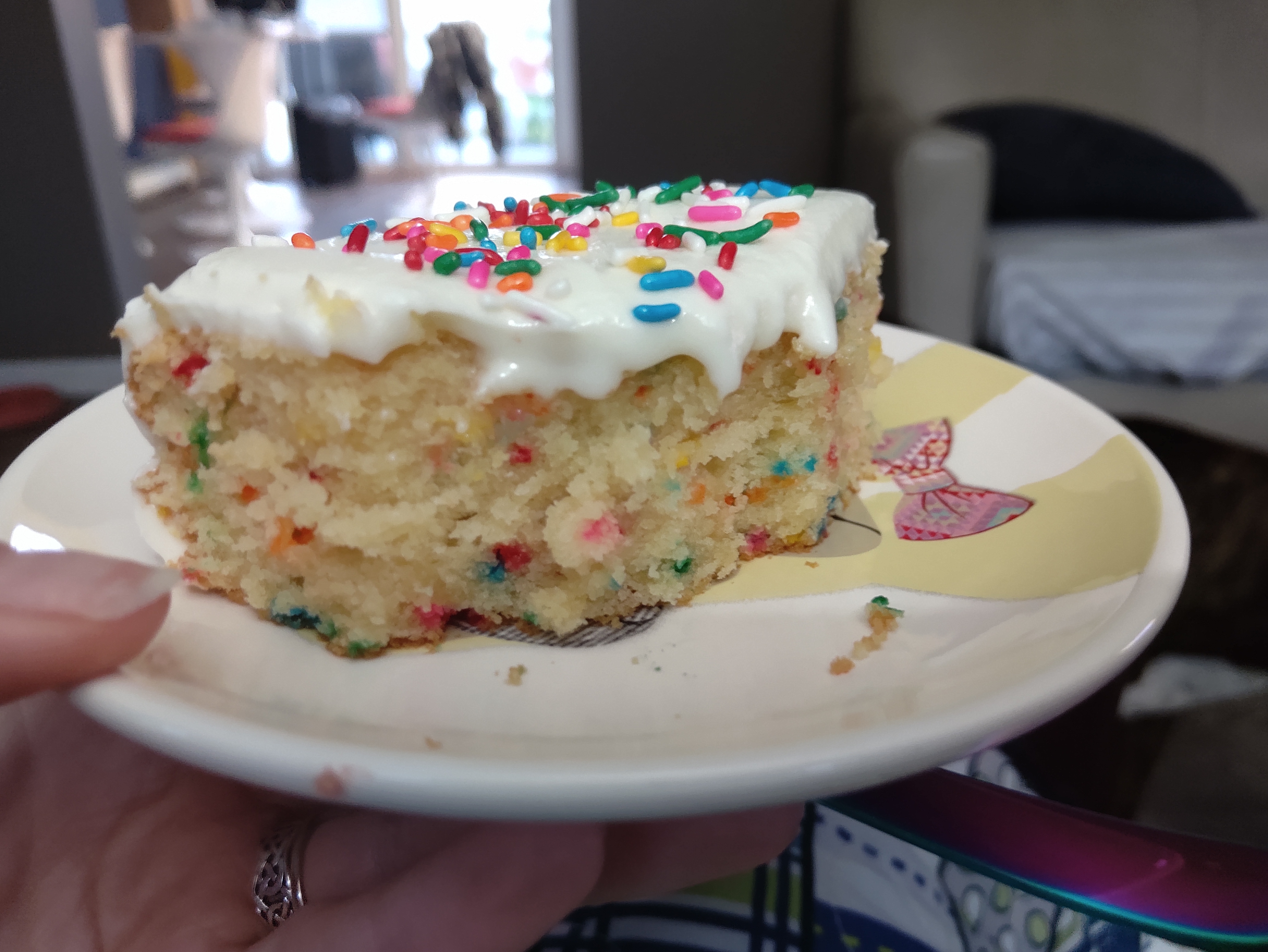 A slice of confetti birthday cake with frosting and sprinkles